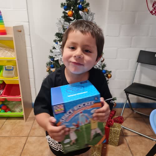 Niño con su regalo frente al árbol de Navidad